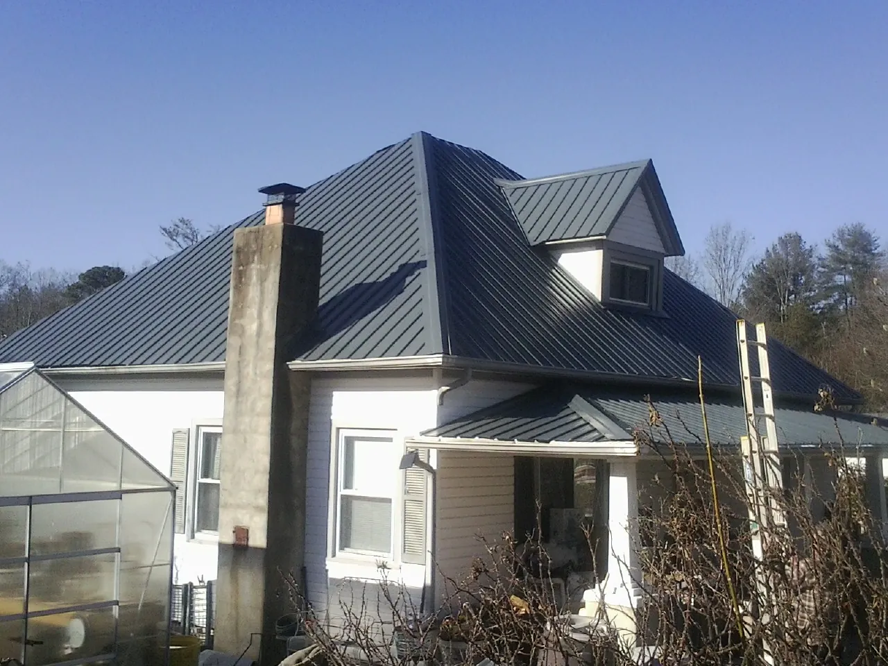 Dark blue standing seam metal roof on a white farmhouse with dormer — Slate & Tile Roof Repair by Roofing Brothers in Chrisney