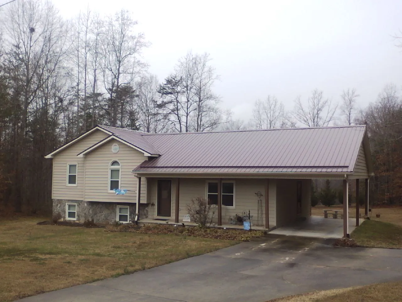 Burgundy metal roof on a tan split level home with an attached carport in Chrisney