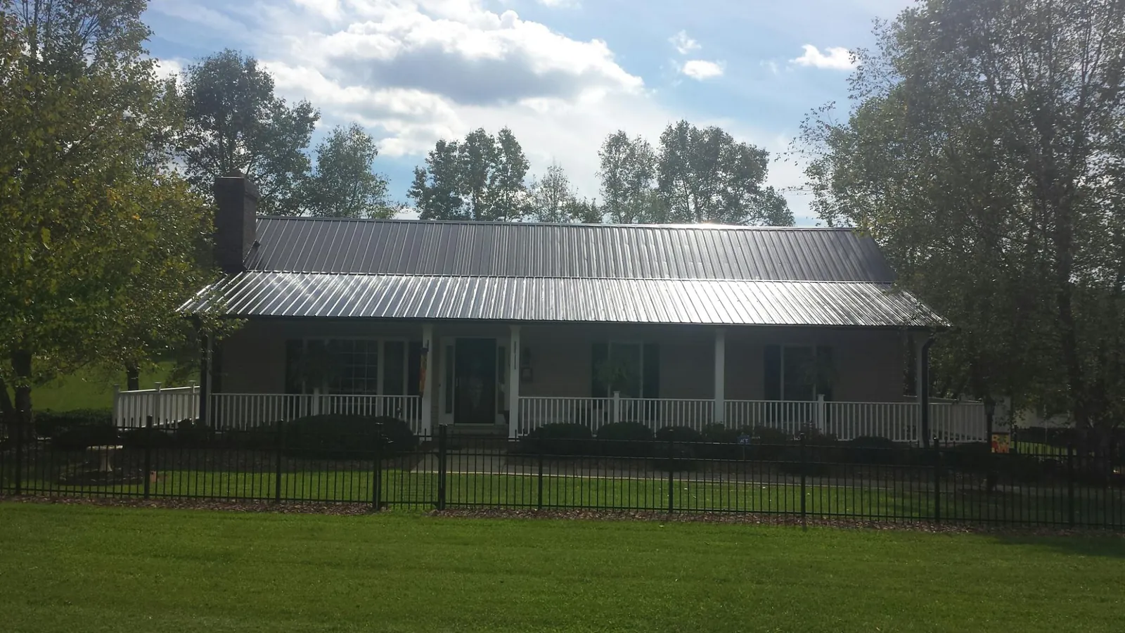 Gray metal roof on a brick ranch with a full width front porch — Gutter Guard Installation work by our crew in Chrisney