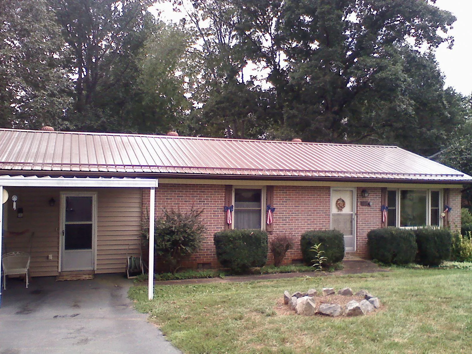 Bronze metal roof and carport on a brick ranch home — Roof Repair work by our crew in Chrisney