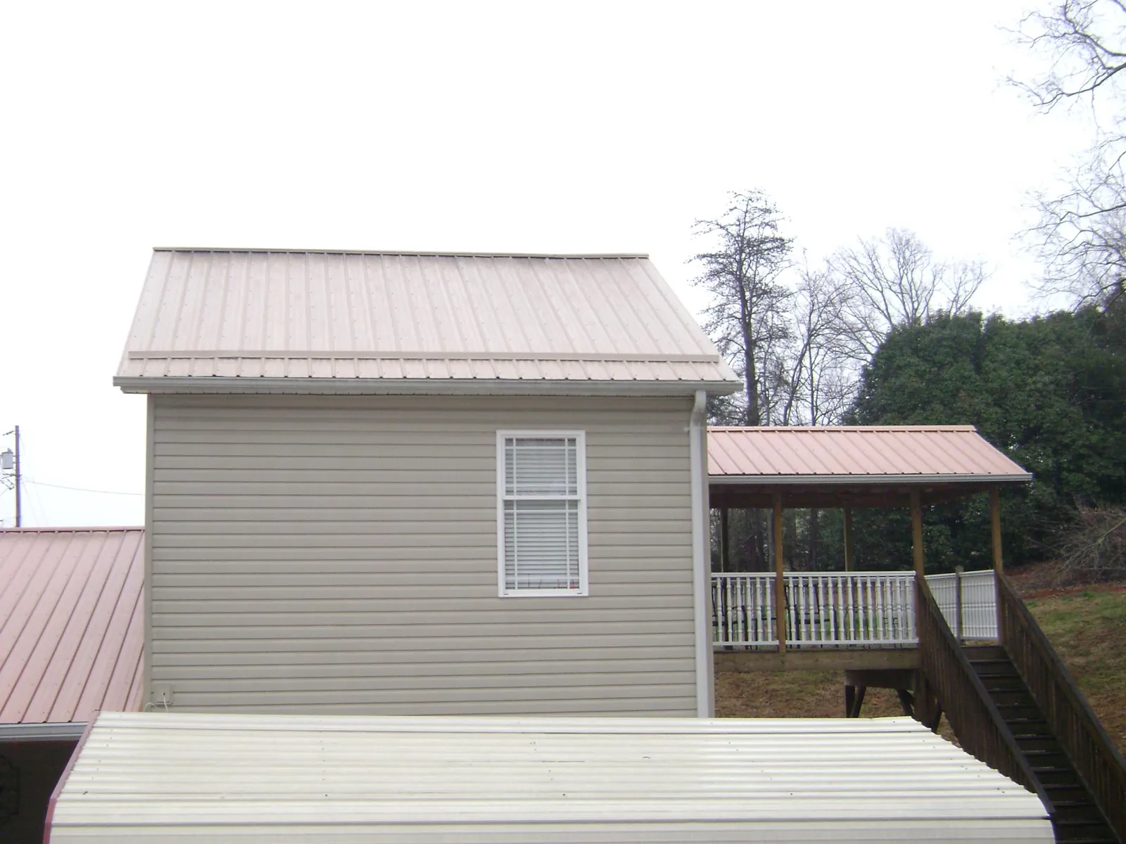 Tan metal roofs on a two story addition and attached porch, from a Roof Replacement job in Chrisney