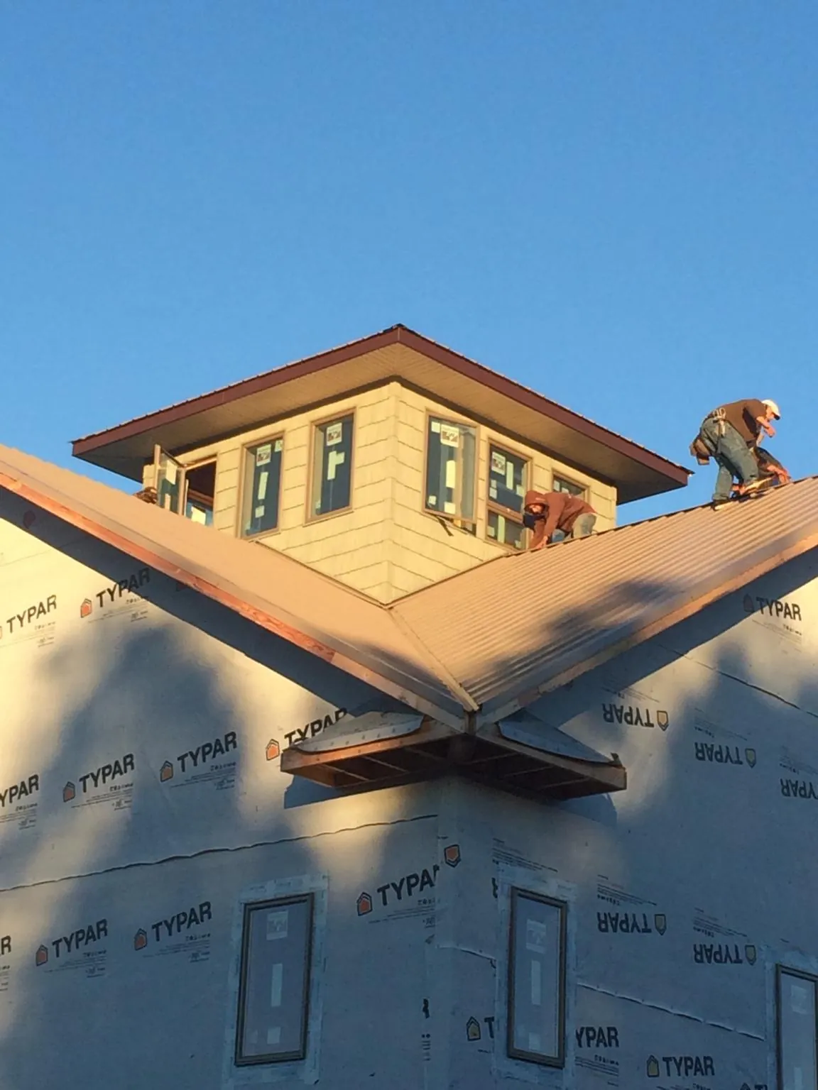 Roofers working around a rooftop cupola on a new metal roof at sunset — Roof Waterproofing in Chrisney by Roofing Brothers